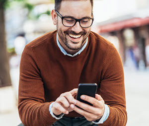 A man smiling while using his smartphone